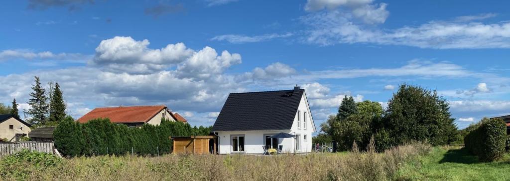 a white house with a black roof in a field at Ferienhaus Kalea in Userin