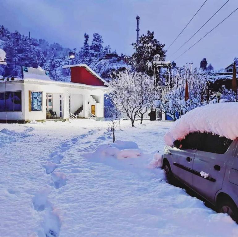 a car covered in snow in front of a house at Hotel Veerjeet Resorts in Doda