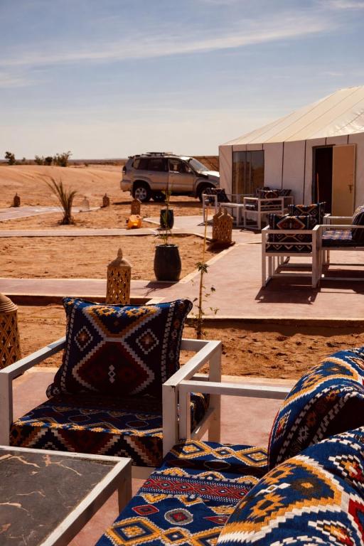 a room with two chairs and a tent in the desert at Hidden luxury Camp in Merzouga
