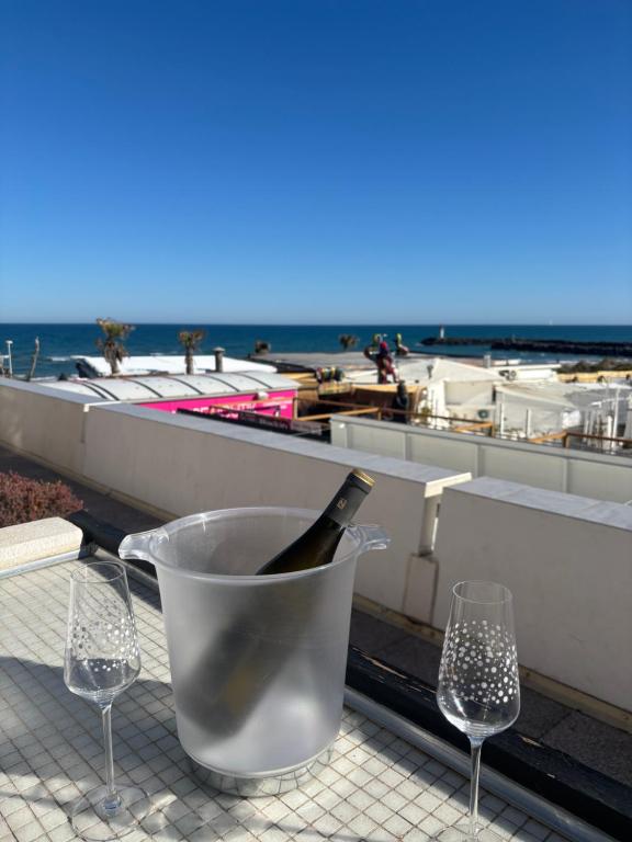 a bottle of wine in a bucket on a table with wine glasses at Sunset in Cap d'Agde