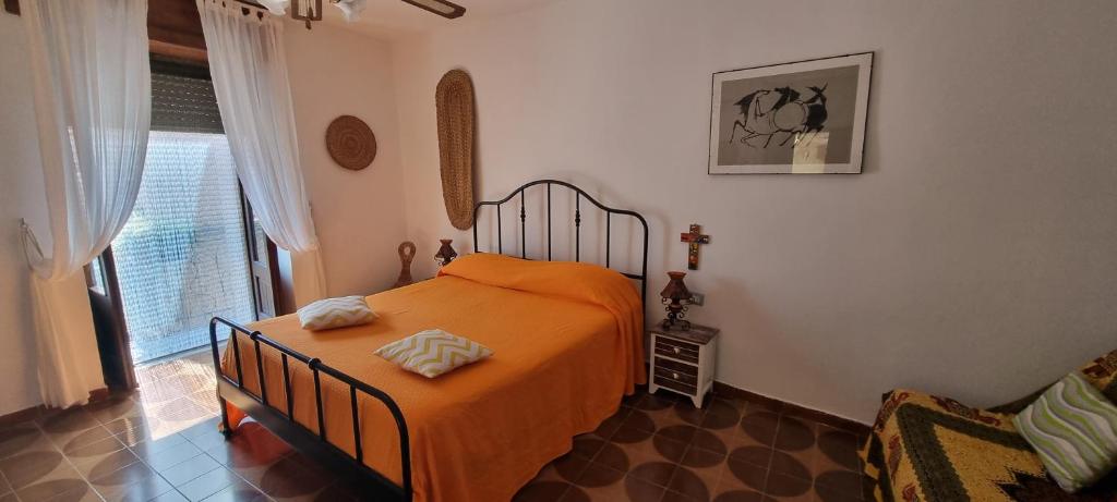 a bedroom with a bed with an orange blanket at Iris in Rodio