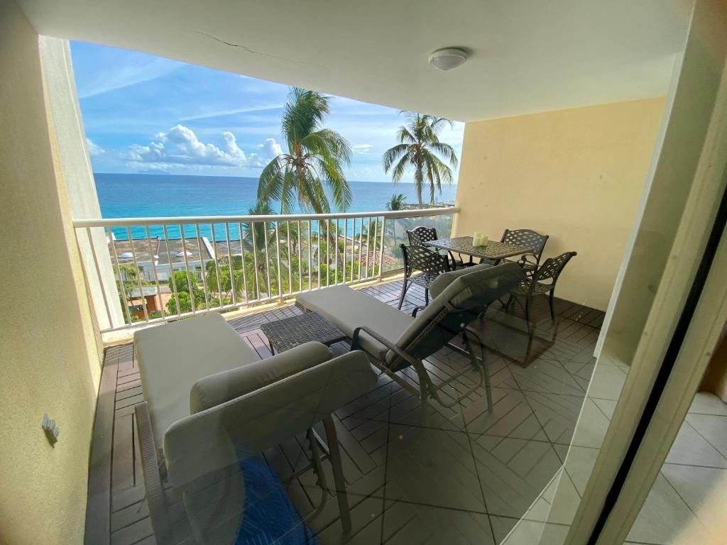 a balcony with a table and chairs and the ocean at Oceanview large studio, pool, walk to Mullet Bay, Cupecoy Beach, walk to dining, free parking in Cupecoy