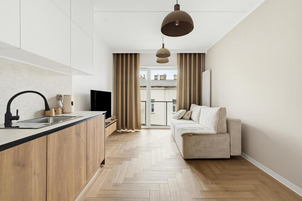 a kitchen with a sink and a couch in a room at Neon Apartments Centrum in Częstochowa