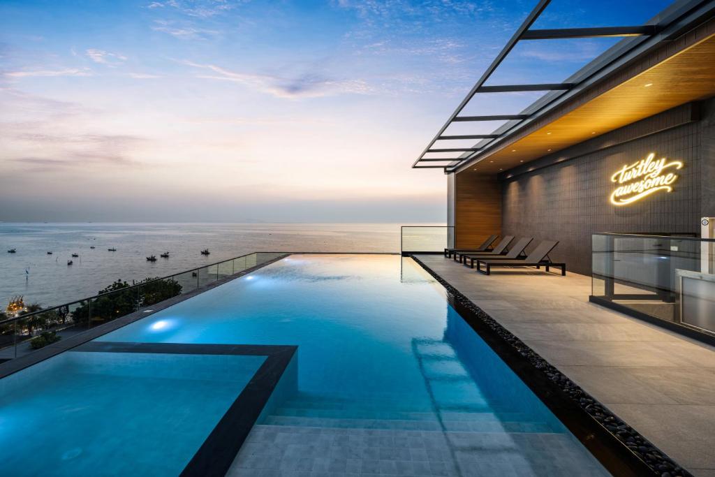 a swimming pool in front of a building with the ocean at The Turtle Hotel Bangsaen in Ban Thai Don (1)