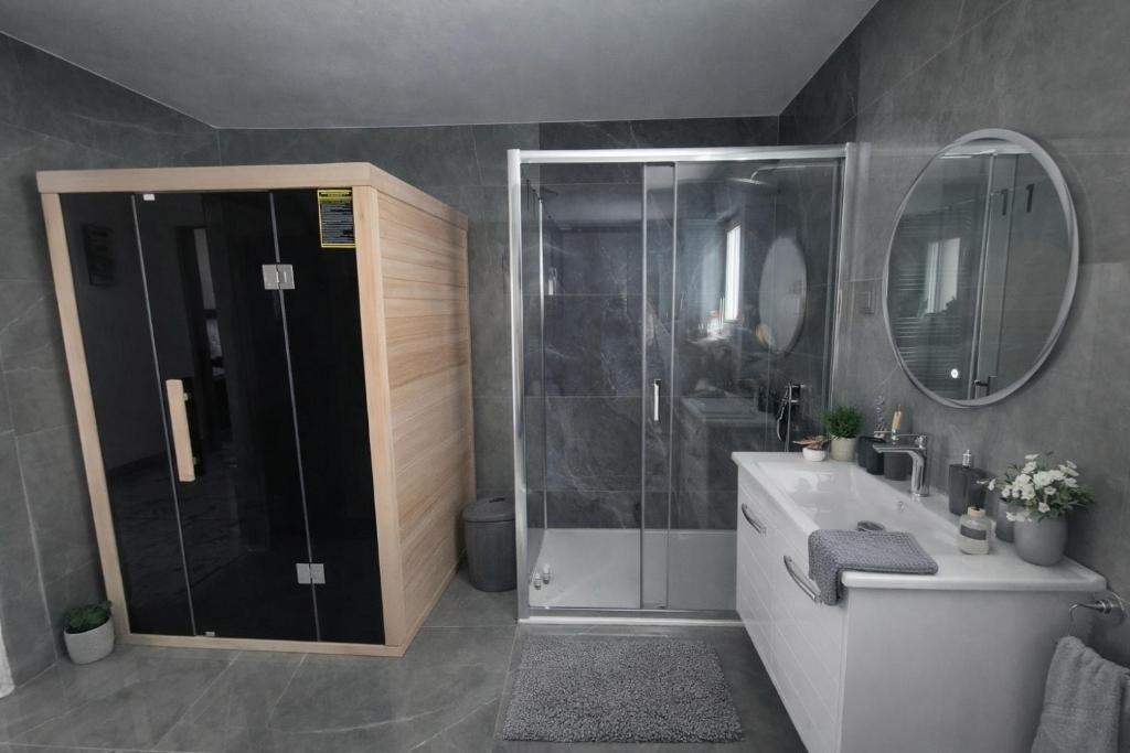 a bathroom with a shower and a sink and a mirror at Plitvice Harmony one - seven person in Smoljanac