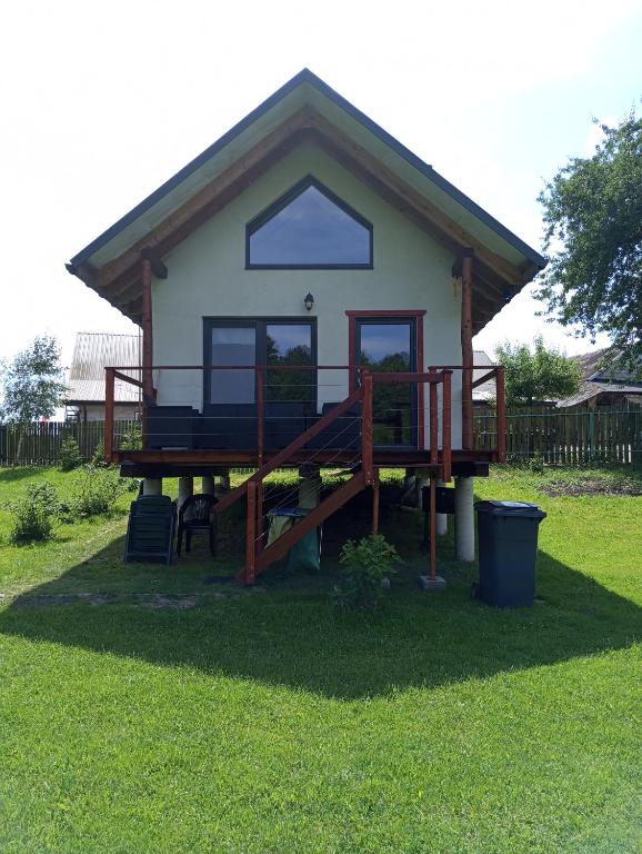 a small house with a large deck in the grass at Olchowym Domek in Gostynin