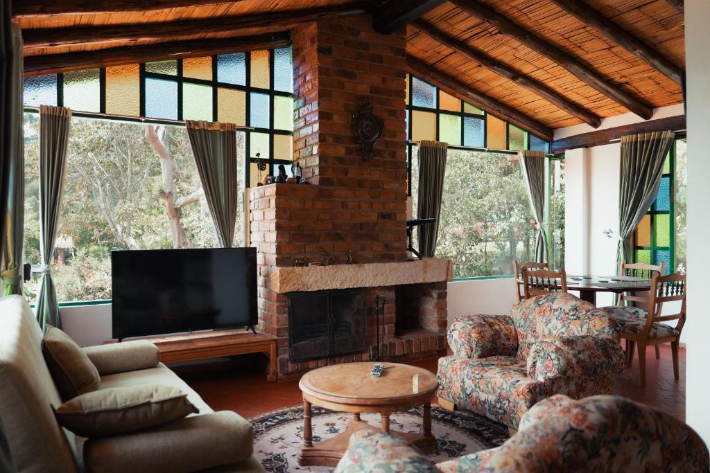 a living room with a fireplace and a tv at Hotel Rokas de Suesca in Suesca