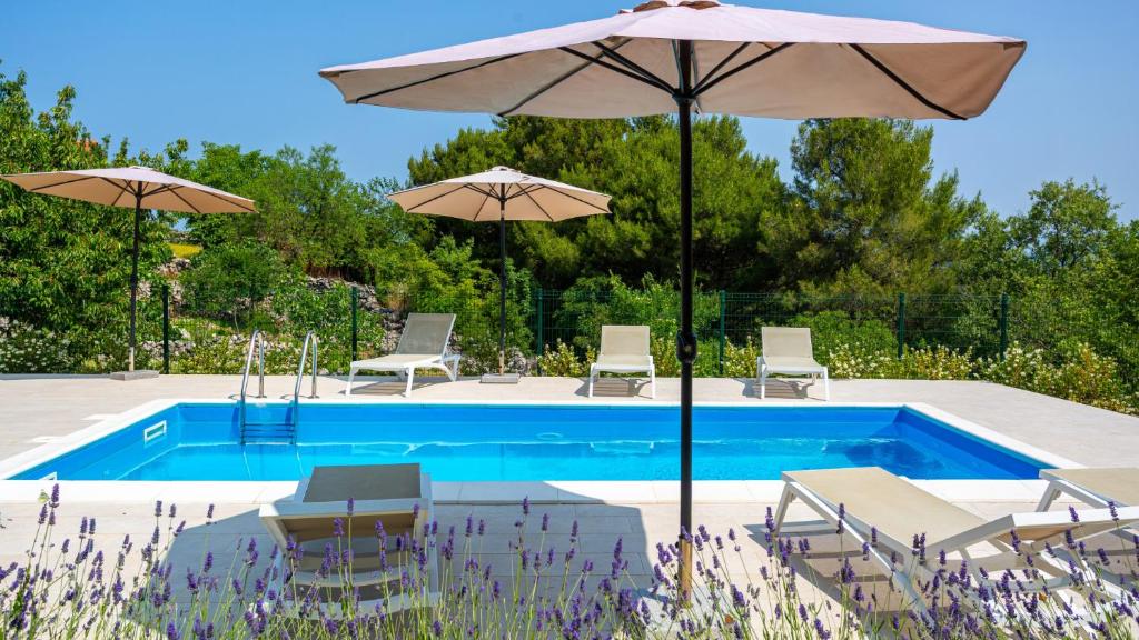 a pool with umbrellas and chairs next to at Casa Tijana by Villas Guide in Krk