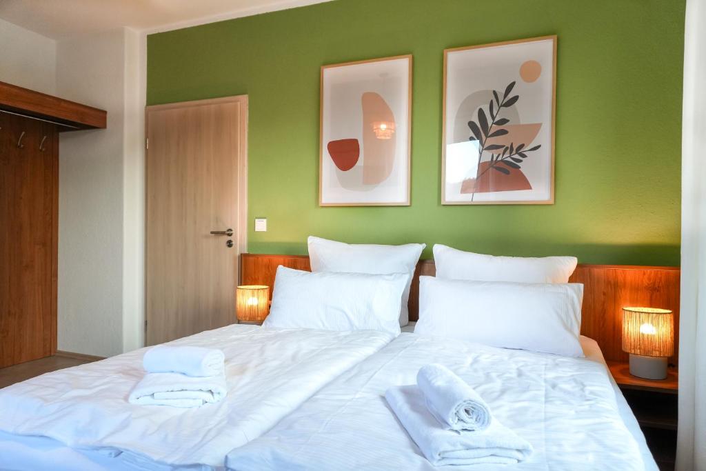 a bedroom with a large white bed with green walls at Ferienwohnung Elbhang mit Stellplatz in Königstein an der Elbe