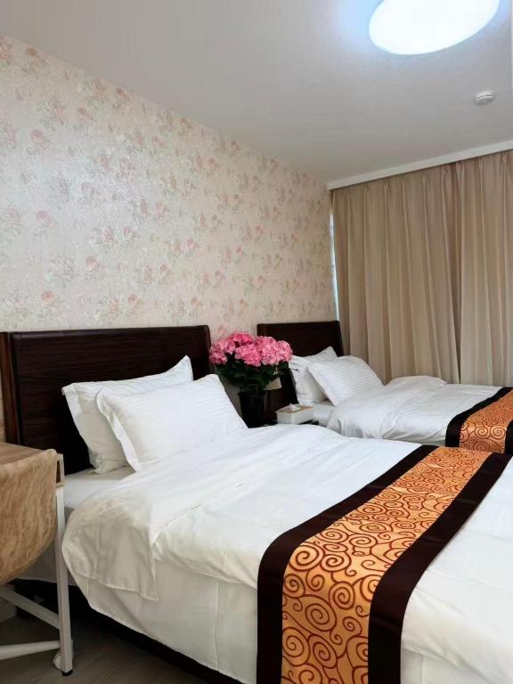 zwei Betten in einem Hotelzimmer mit rosa Blumen in der Unterkunft MUTSUMI Hotel in Saga