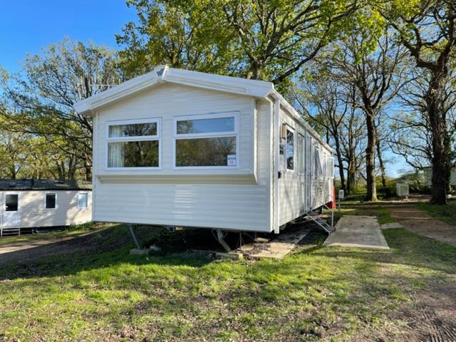 a small white tiny house sitting on the grass at Stylish large static caravan gold rated 3BR Slp 8 Thorness Bay in Porchfield