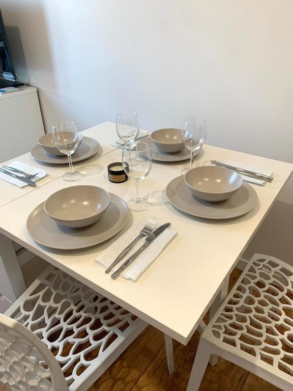 a white table with plates and wine glasses on it at Charme et confort in Montévrain