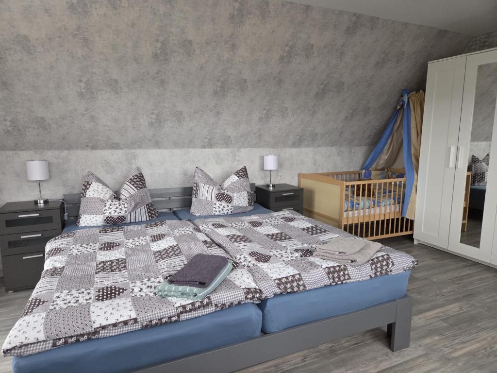 a bedroom with a bed with a blanket and a crib at Ferienwohnung, Urlaub im Frankenwald in Konradsreuth