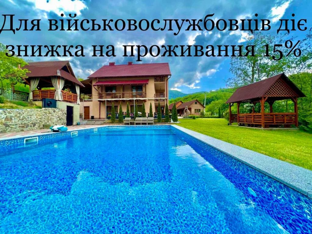 a large blue swimming pool in front of a house at Купецький Двір in Mizhhirya