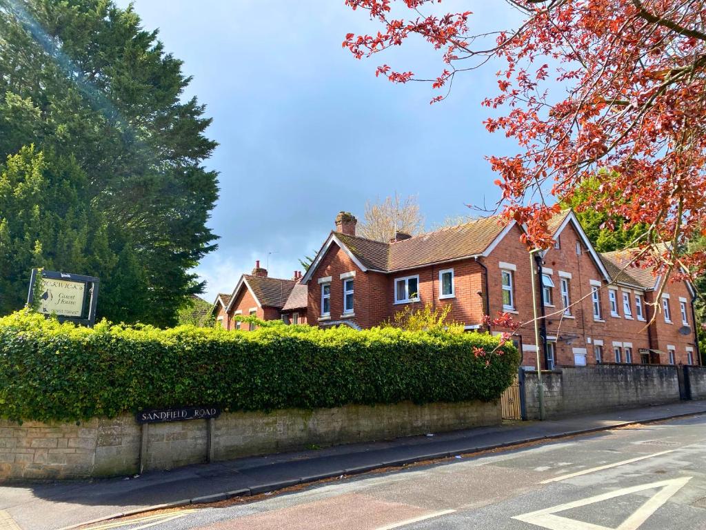 a brick house with a hedge in front of a street at Pickwicks Guest House in Oxford