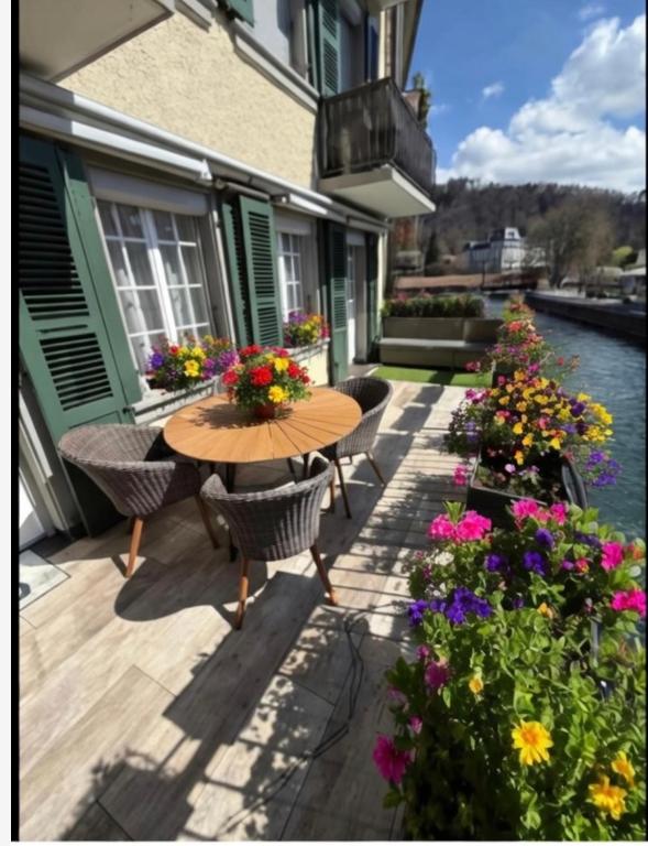 eine Terrasse mit Tisch, Stühlen und Blumen in der Unterkunft Emma in Thun