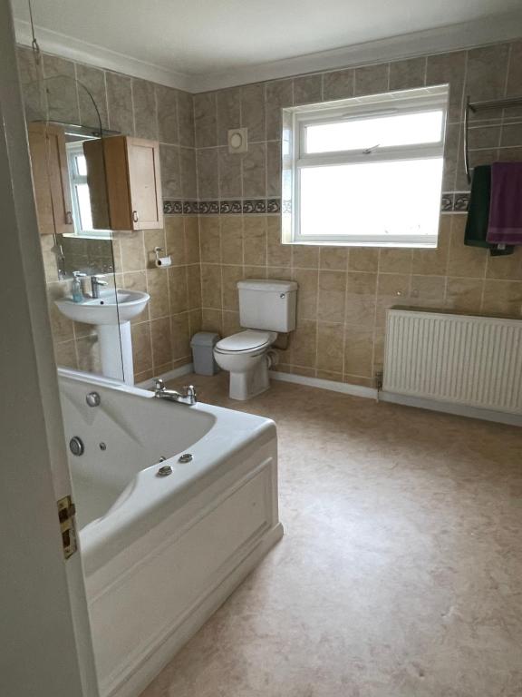 a bathroom with a tub and a toilet and a sink at Selsey Home in Selsey