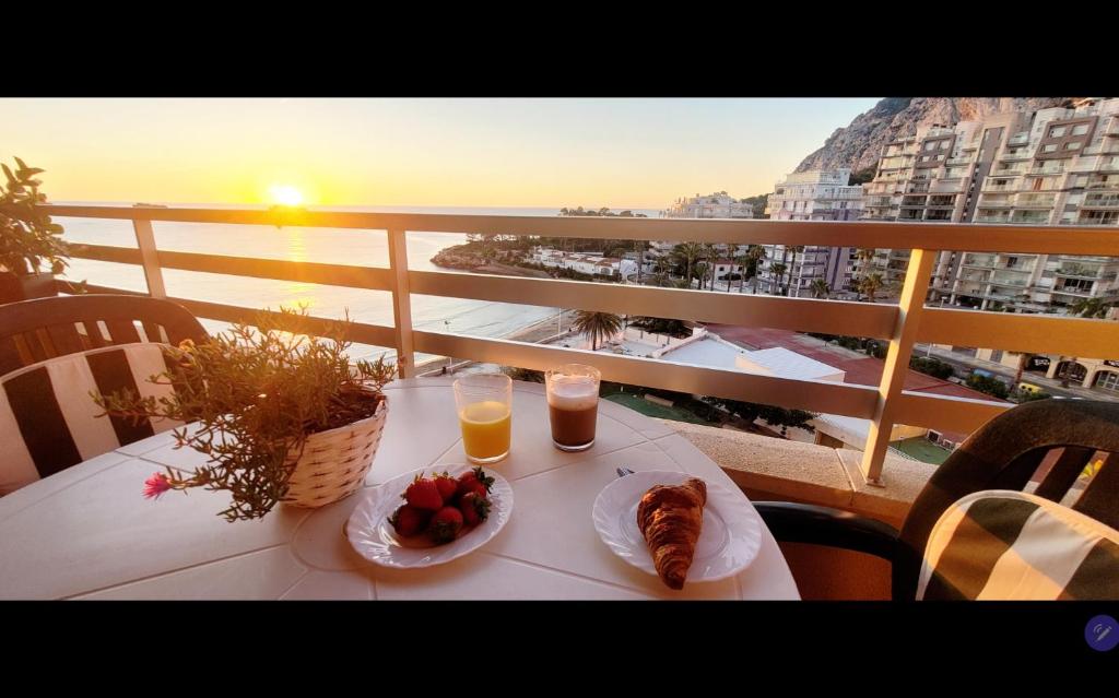 a table with a plate of food and two glasses of orange juice at Calpe vistas al mar in Ifach