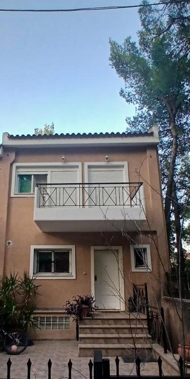 a house with a balcony and stairs in front of it at Agios Stefanos TwoStory Maisonette in Néa Zoryiáni