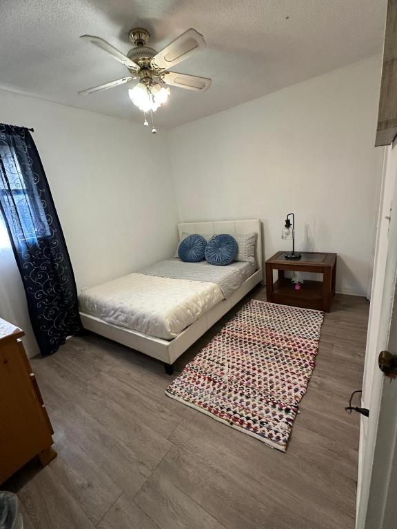 a room with a bed with a ceiling fan and a rug at Hermosas habitaciones in Pembroke Pines