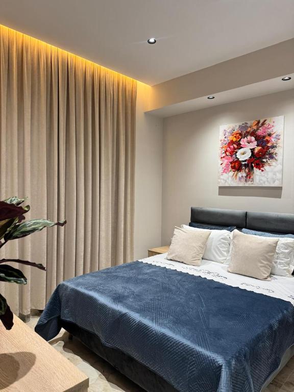a bedroom with a blue bed with a painting on the wall at Alesia's Guesthouse in Vlorë