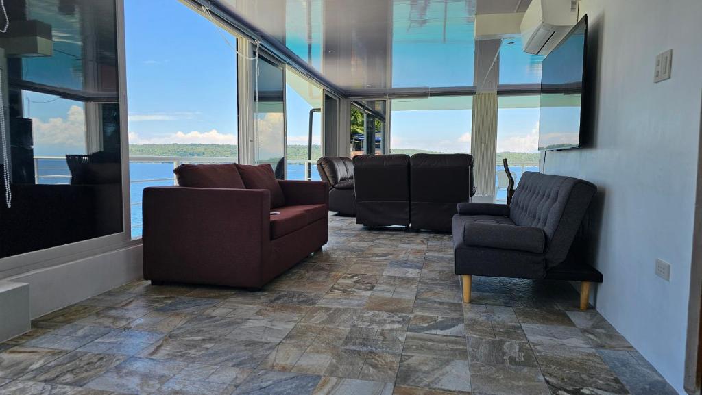 a waiting room with chairs and tables and windows at Lydia's House, Samal beach front apartments in Kaputian
