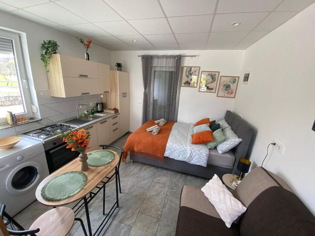 a bedroom with a bed and a kitchen with a table at Studio Angelina in Prestranek