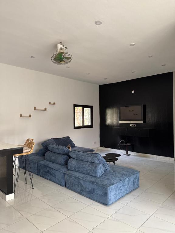 a living room with a blue couch and a flat screen tv at Chez Sira in Warang