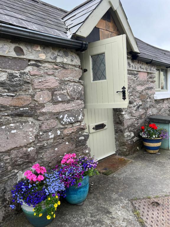 a stone house with a door and some flowers at Ancaire Studio in Schull