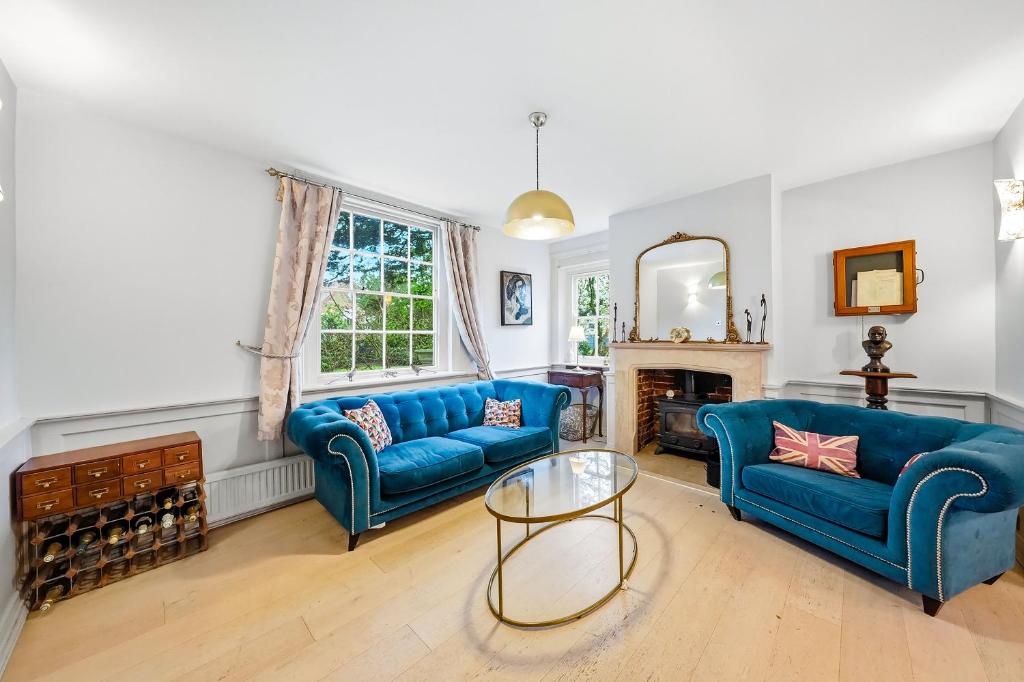 a living room with two blue couches and a fireplace at Lee's Historic Mansion in Cheshunt
