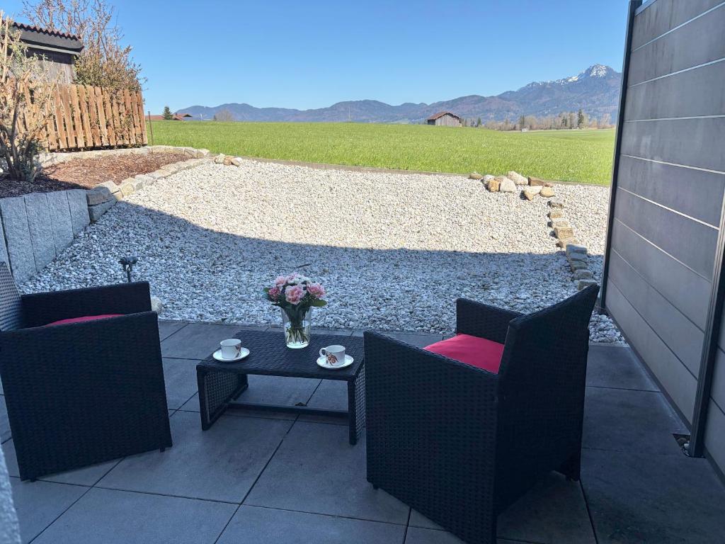 a patio with two chairs and a table with a vase of flowers at Studio mit Alpenblick und privaten Terrasse in Kleinweil