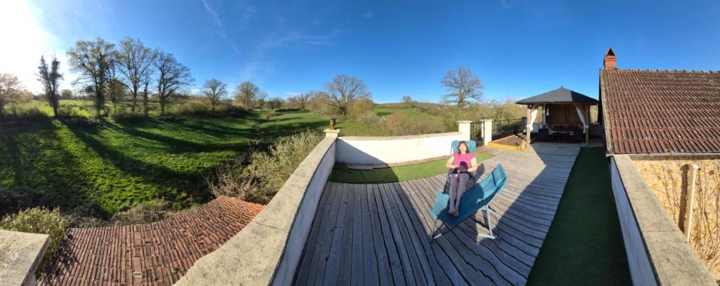 a woman is sitting on a bridge over a river at La Perle Secrète in Theneuille