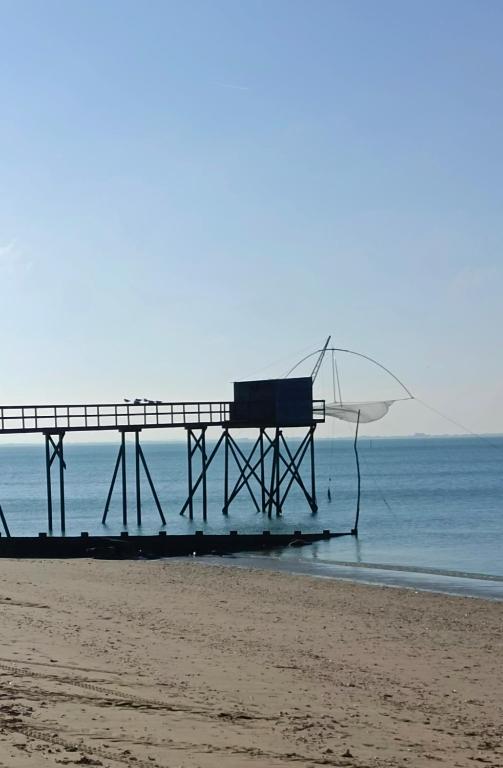 a pier on the beach with the ocean behind it at le Pressoir Doretz in Arthon-en-Retz