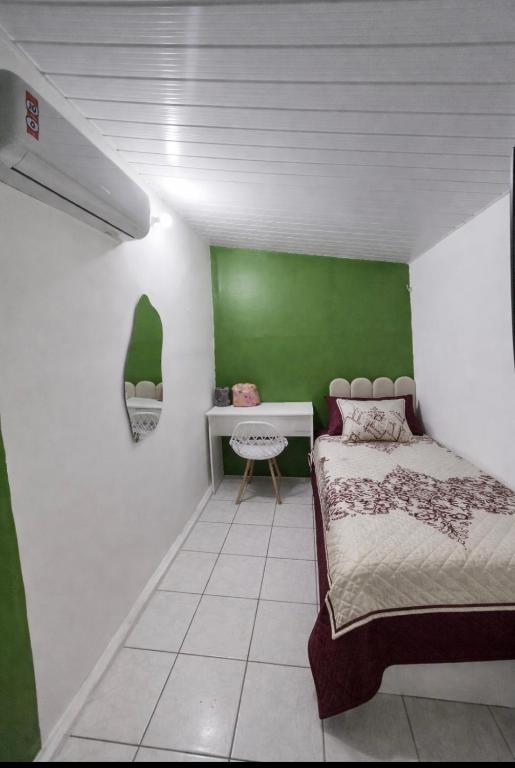 a bedroom with a bed and a green wall at Quarto solteiro custo-benefício in São Luís