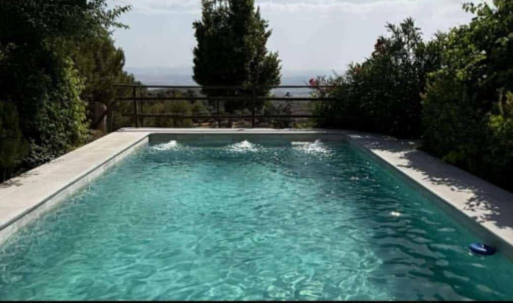 a swimming pool with blue water in a yard at Casa rural con piscina privada en Nívar, vistas espectaculares a 15 min de Granada in Nívar