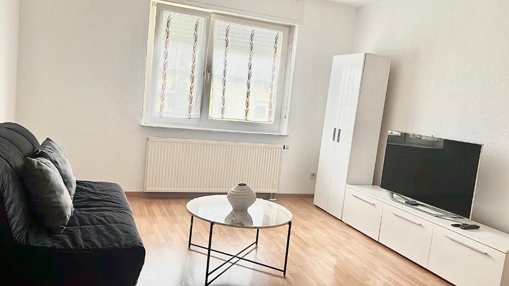 a living room with a couch and a table and a tv at Ferienwohnung Sophie in Weil am Rhein