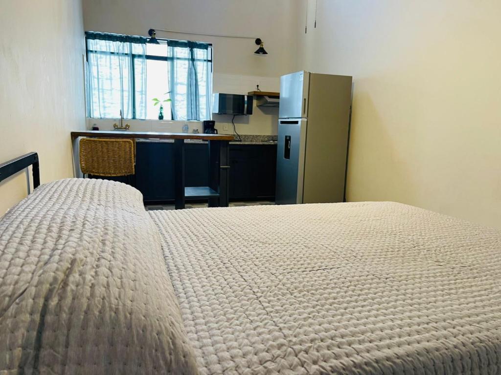 a room with a bed and a kitchen with a refrigerator at Apartamento 25 Centrico Chapala in Chapala