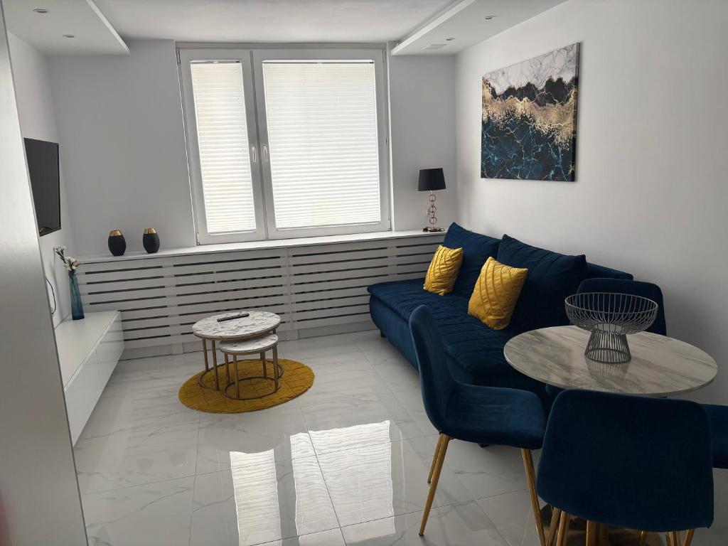 a living room with a blue couch and a table at Luksusowy Apartament Giżycko in Giżycko