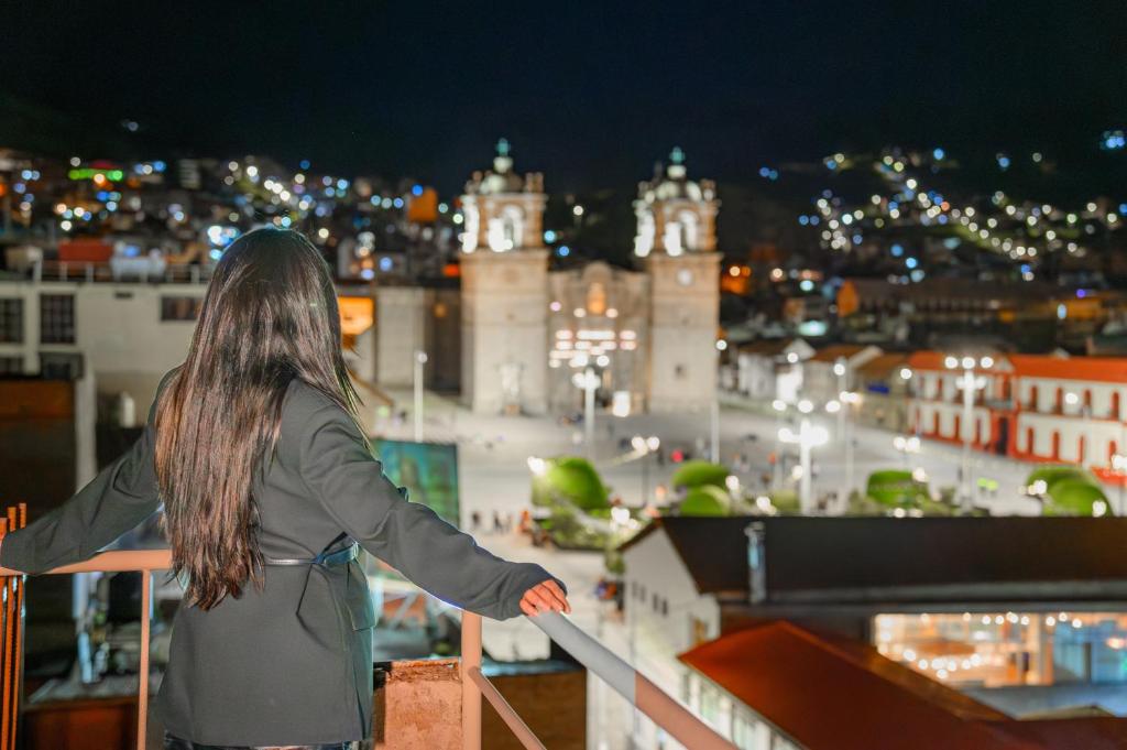 a woman standing on a ledge overlooking a city at night at Sol Plaza Hotel in Puno