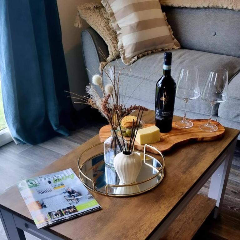 a table with a bottle of wine and wine glasses at 19 the Coombe Charming, 2-Bedroom Family Chalet with Parking, Near Bude Beaches in Bude