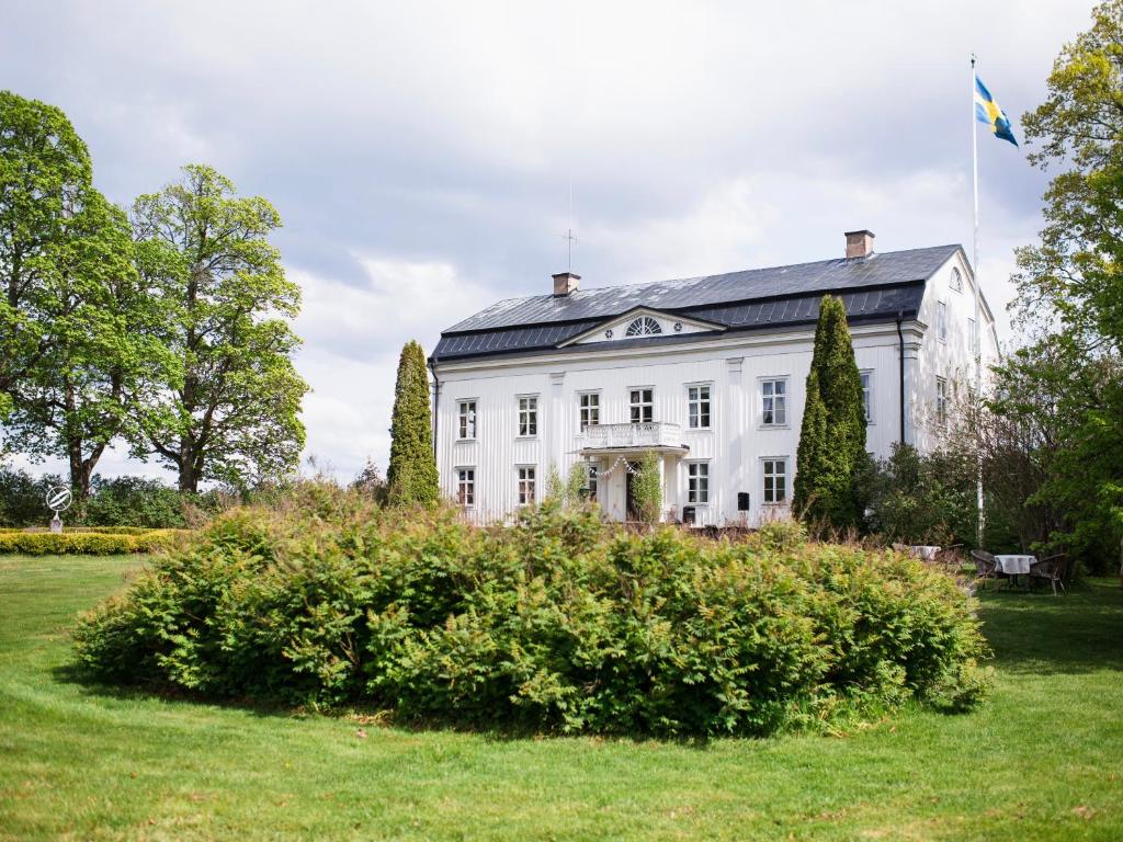 a white house with a flag on top of it at Wallby Säteri in Skirö