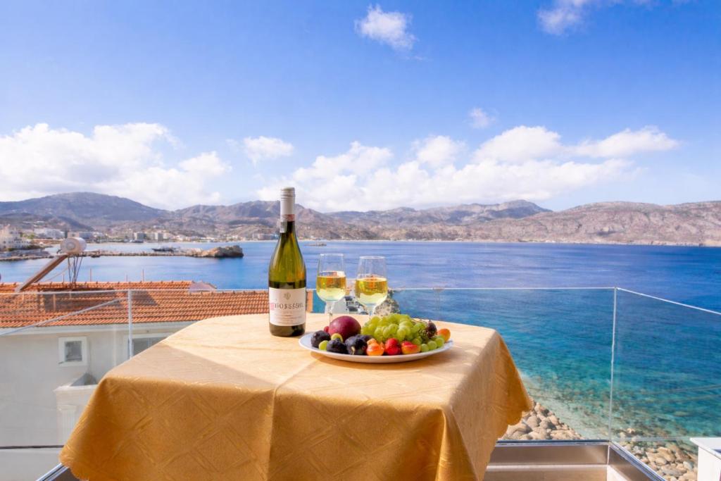 a table with a bottle of wine and a bowl of fruit at Dolphin Hotel Apartments in Karpathos