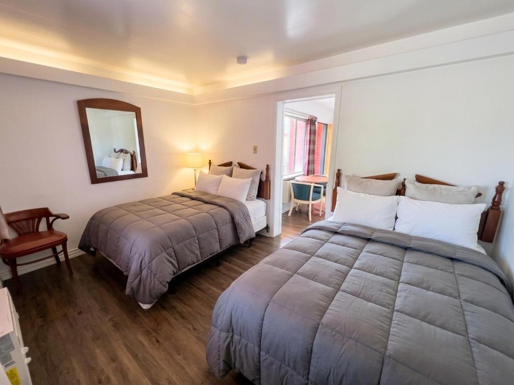 a hotel room with two beds and a mirror at Persepolis Inn in Niagara Falls
