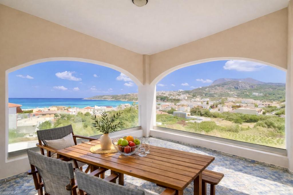 a dining room with a table and a view of the ocean at Elysian Seaside Villa in Almyrida