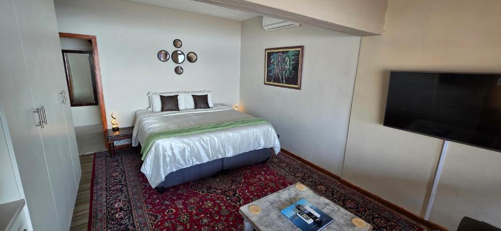 a bedroom with a bed and a flat screen tv at Apex Ocean and Mountainview in Gordonʼs Bay