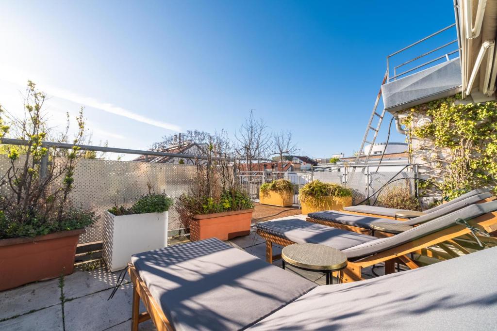 a patio with lounge chairs and tables on a balcony at Sky Garden Vienna in Vienna