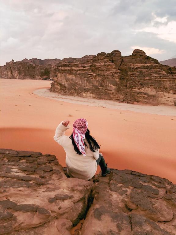 a woman sitting on a rock looking at the beach at Bedouin Life Camp in Aqaba