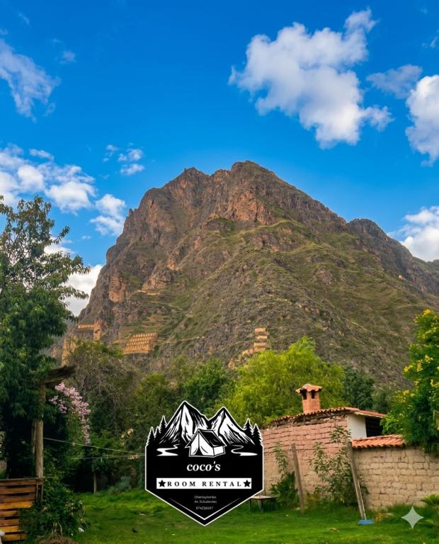 a mountain in the background with a sign in the foreground at Coco's vibes in Ollantaytambo