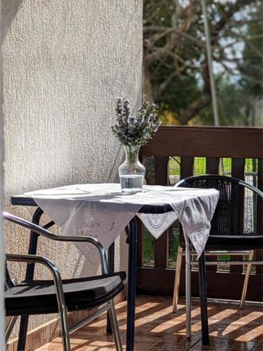 a table and chairs with a vase of flowers on a porch at Međugorje Quit Hideaway in Botići