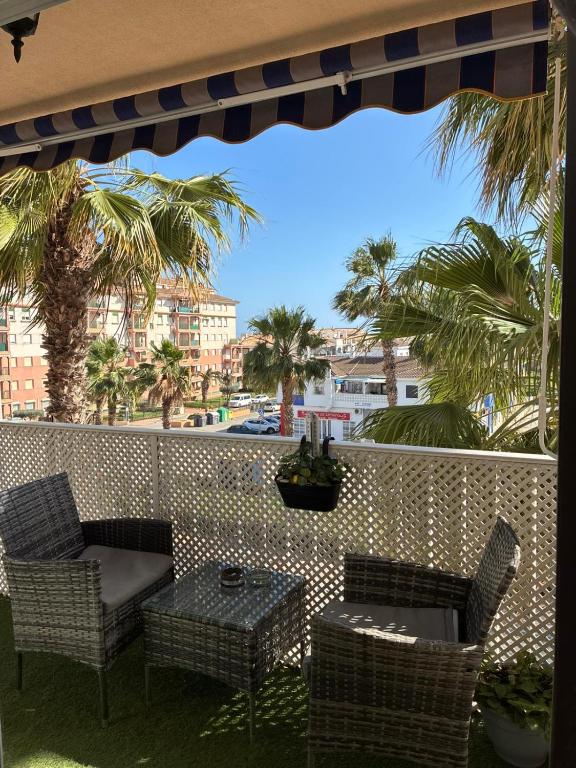 a patio with chairs and a table and palm trees at Los Lentiscares Apartment in Torrox Costa